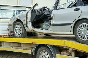 Crashed car loading into tow truck after traffic accident on road photo