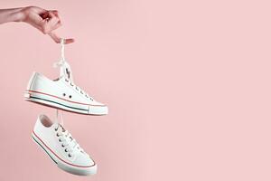 White casual sneakers on pink background, creative minimalism photo