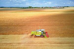 aéreo ver de trabajando cosecha combinar en trigo campo, cosecha temporada foto