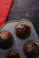 Just baked chocolate muffins in tray, homemade comfort food recipe photo
