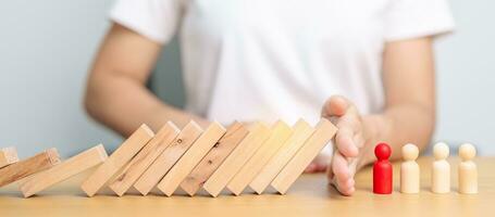 Hand stop falling wood domino blocks on table. Crisis, fall Business, Risk management, Economic recession, Strategy and solutions concept photo