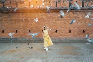 joven asiático mujer viajero en amarillo vestir con sombrero y bolso de viaje en eso pae puerta, turista visitar a el antiguo ciudad en chang Mai, tailandia Asia viajar, vacaciones y verano fiesta concepto foto