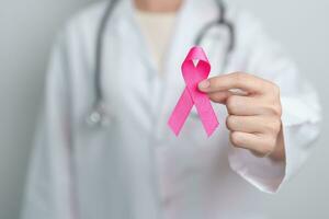 Pink October Breast Cancer Awareness month, doctor with pink Ribbon in hospital for support people life and illness. National cancer survivors month, Mother and World cancer day concept photo