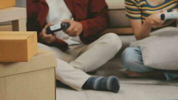 Moving to a new apartment. Happy newlyweds bought their first home, stand in the living room among the boxes, hold cardboard boxes in their hands, prepare to unpack things, look at the camera, smile video