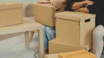 Moving to a new apartment. Happy newlyweds bought their first home, stand in the living room among the boxes, hold cardboard boxes in their hands, prepare to unpack things, look at the camera, smile video