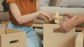 Moving to a new apartment. Happy newlyweds bought their first home, stand in the living room among the boxes, hold cardboard boxes in their hands, prepare to unpack things, look at the camera, smile video