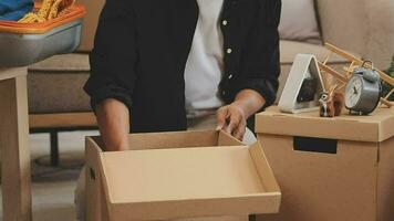 en mouvement à une Nouveau appartement. content jeunes mariés acheté leur premier maison, supporter dans le vivant pièce parmi le des boites, tenir papier carton des boites dans leur mains, préparer à déballer choses, Regardez à le caméra, sourire video