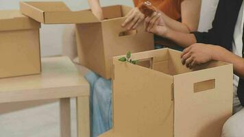 Moviente a un nuevo departamento. contento recién casados compró su primero hogar, estar en el vivo habitación entre el cajas, sostener cartulina cajas en su manos, preparar a deshacer cosas, Mira a el cámara, sonrisa video