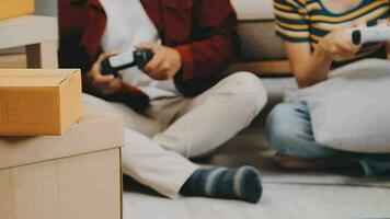 Two people couple interracial family ameste in living room in new apartment open cardboard boxes receive parcels with orders from internet store with new interior items rejoice at courier delivery video