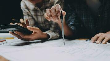 Image of team engineer checks construction blueprints on new project with engineering tools at desk in office. video