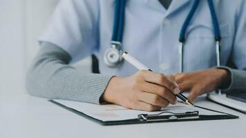 Woman patient visiting female doctor at clinic office. Medical work writes a prescription on a table in a hospital. video