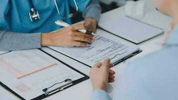 vrouw geduldig bezoekende vrouw dokter Bij kliniek kantoor. medisch werk schrijft een voorschrift Aan een tafel in een ziekenhuis. video