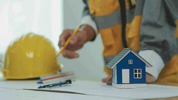 costruzione e struttura concetto di ingegnere o architetto incontro per progetto Lavorando con compagno e ingegneria utensili su modello edificio e planimetria nel Lavorando luogo, contrarre per tutti e due aziende. video