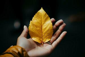 mano suavemente sostiene un dorado hoja, un símbolo de de otoño fugaz belleza ai generado foto