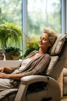 Senior woman lounging and napping on an electric massage chair in the living room photo