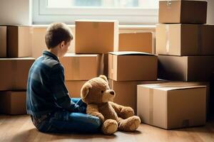 Single child looking down hugging teddy bear amidst moving boxes photo