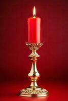 Golden mid-century candle holder with a glowing flame enhancing Christmas nostalgia isolated on a festive red gradient background photo