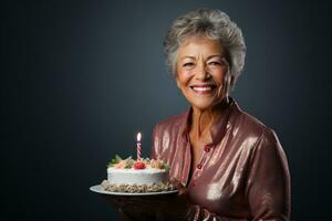 an elderly woman holding a birthday cake with several candles on bokeh style background photo