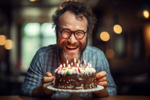 a man holding a birthday cake with several candles on bokeh style background photo