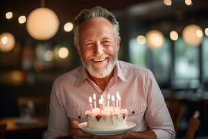 an elderly man holding a birthday cake with several candles on bokeh style background photo