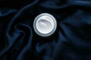 Luxury face cream jar on a dark blue silk photo