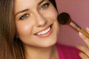 Beautiful young woman applying cosmetic powder product with make-up bamboo brush, beauty, makeup and skincare cosmetics model face portrait on pink background photo