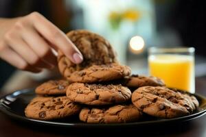 A close up of a hand grabbing chocolate cookies, while holding orange juice AI Generated photo