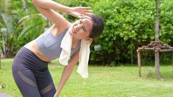 sport asiatico donna prende stanco e ottenere dare le vertigini, sentire cattivo dolore e soffrire a partire dal calore ictus all'aperto quando jogging o esercizio all'aperto con forte luce del sole nel estate stagione. colpo di calore e calore onda concetto. video