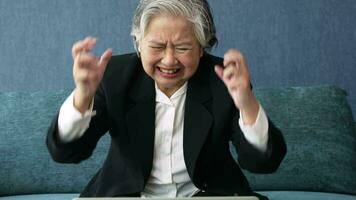 Overworked tired old lady holding head feeling headache. Asian senior business woman stress from hard work. Frustrated business woman thinks seated at workplace, feel distressed looks helpless concept video