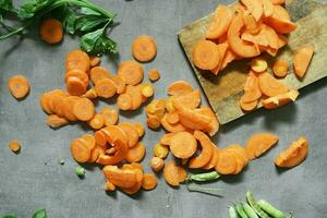 Fresh carrot vegetable pieces on concrete background photo