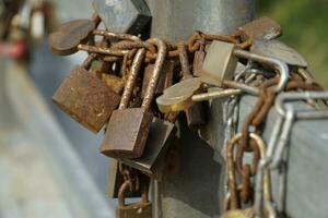 Many Rusty Padlocks Closed on Bridge Fence - Love Concept photo