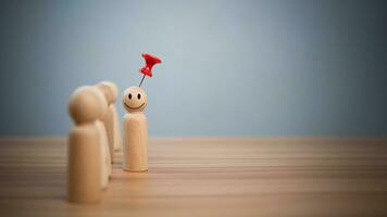 Business and human resources concept for leadership and team leader. A red pin pinned on one wooden doll stands apart and stands out from the crowd. photo