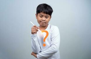 A boy in a white shirt is holding a white pen on a white background. Shows thinking, pondering, and considering options. photo