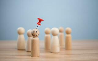 Business and human resources concept for leadership and team leader. A red pin pinned on one wooden doll stands apart and stands out from the crowd. photo