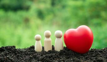 Happy home concept. A family of wooden dolls and a red heart. Indicates happiness and love in the house. photo