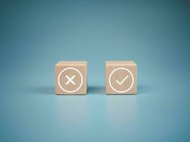 Wooden blocks with wrong and right symbols on light blue background. photo