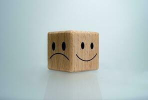 Mental health and emotional state concept, Smile face  and sad face on wooden block cube for positive mindset selection concept. photo