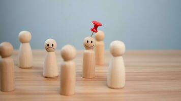 Business and human resources concept for leadership and team leader. A red pin pinned on one wooden doll stands apart and stands out from the crowd. photo