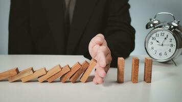 Risk management concept. Businessman hand stopping dominoes effect for business. photo