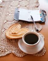 blanco taza de negro café y un dulce mantecoso Galleta en el mesa foto