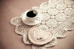 blanco taza de negro café y un dulce mantecoso Galleta en el mesa foto