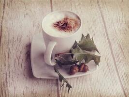 hot autumn coffee with foam and chestnuts on a wooden background photo