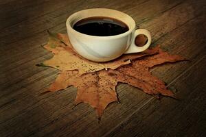 hot autumn black espresso coffee on a wooden table and autumn maple leaves photo