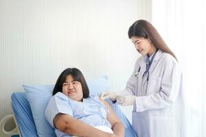 Beautiful asian female doctor Injecting an injection to an obese woman who is lying in bed Treat disease and build immunity. Hospital medical service concept photo