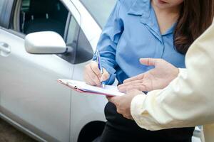 A woman driving a car has an accident during the rain. Signing the auto insurance claim document with an insurance agent. Concept a road traffic photo