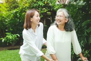 Asian elderly woman doing physical therapy There is a daughter to help support in walking and exercising. They were both in the front yard. concept of caring for the elderly to be healthy photo