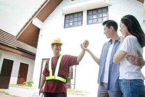 asiático hombres y mujer parejas obtener el casa llaves desde el hogar inspección ingeniero. ellos fueron ambos contento con su nuevo casas el concepto de comenzando un familia. foto