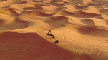 A drone flies over quad bikes driving through the sand dunes of the desert in the United Arab Emirates. Aerial view video