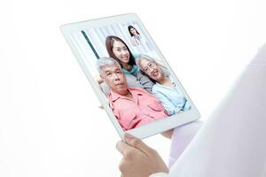 el concepto de conectando con comunicación mediante en línea tecnología. un hembra médico con un tableta charla en línea, tratar asiático mayor pacientes mediante vídeo llamadas blanco antecedentes. foto