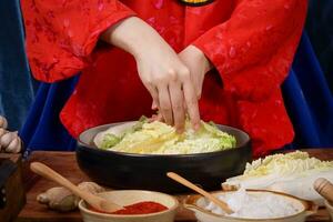 Korean women wear traditional red hanboks, make kimchi by tearing the Chinese cabbage. The concept of cooking fermented foods that are charming and fragrant, Asian cuisine from folk wisdom photo